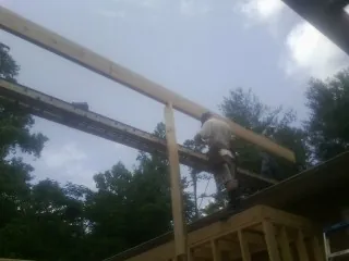 Carpenter setting a ridge beam over a new addition frame — Ice Dam Removal by Roofing Brothers in Canute