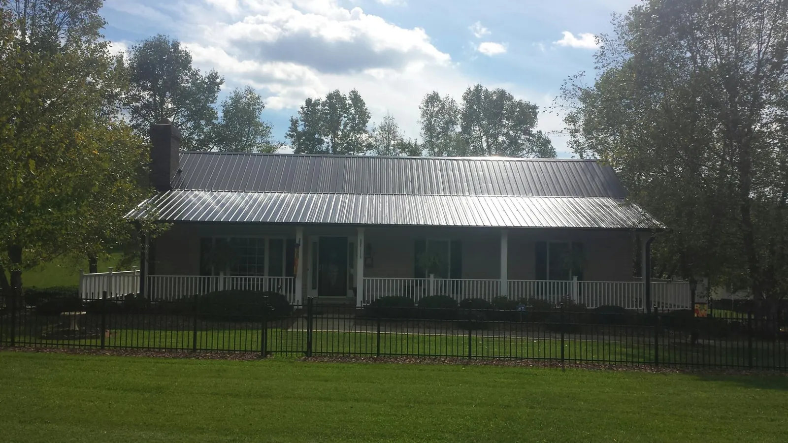 Gray metal roof on a brick ranch with a full width front porch — Gutter Guard Installation work by our crew in Canute