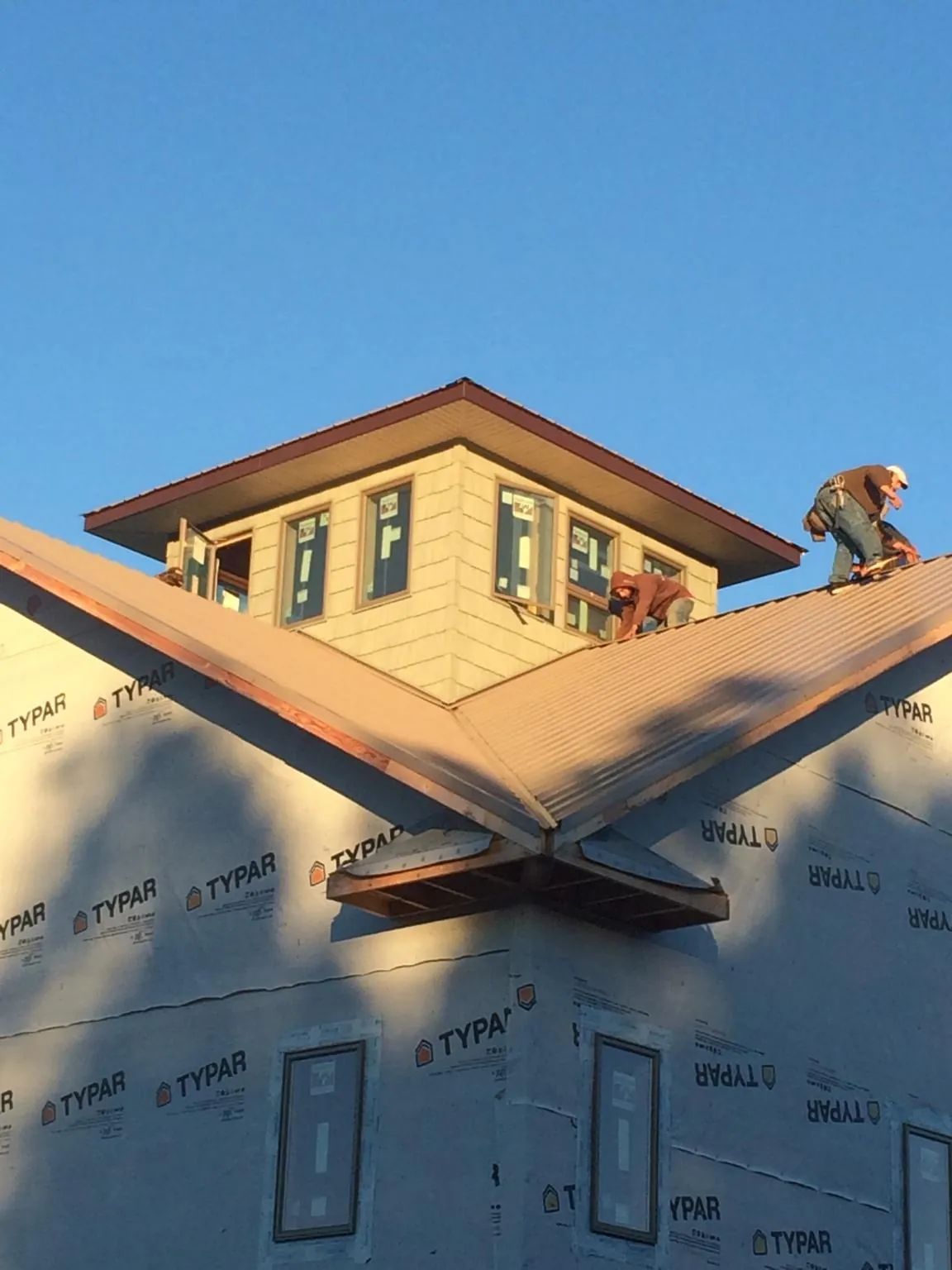 Roofers working around a rooftop cupola on a new metal roof at sunset — Roof Waterproofing in Canute by Roofing Brothers